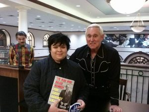 A Wikimedia Commons photo taken from Flickr shows someone with Roger Stone holding his book, "The Man Who Killed Kennedy, the Case against LBJ."